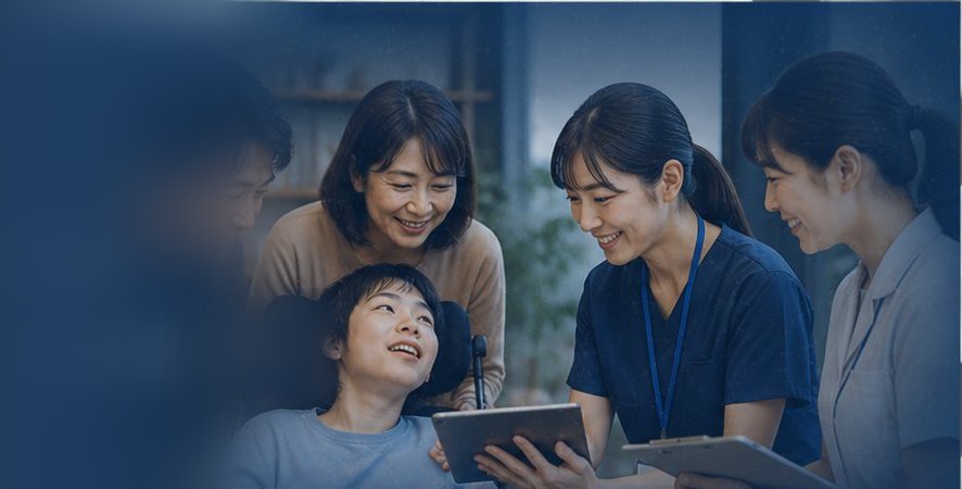 車いすの男の子を囲み、ご家族と看護師がタブレットの記録を一緒に見ている様子